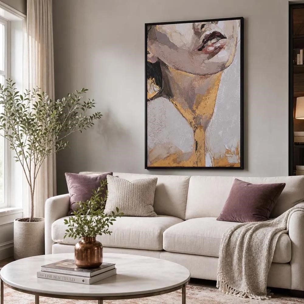 Gold framed line drawing lit by a floor lamp above a gray sectional on a large wall